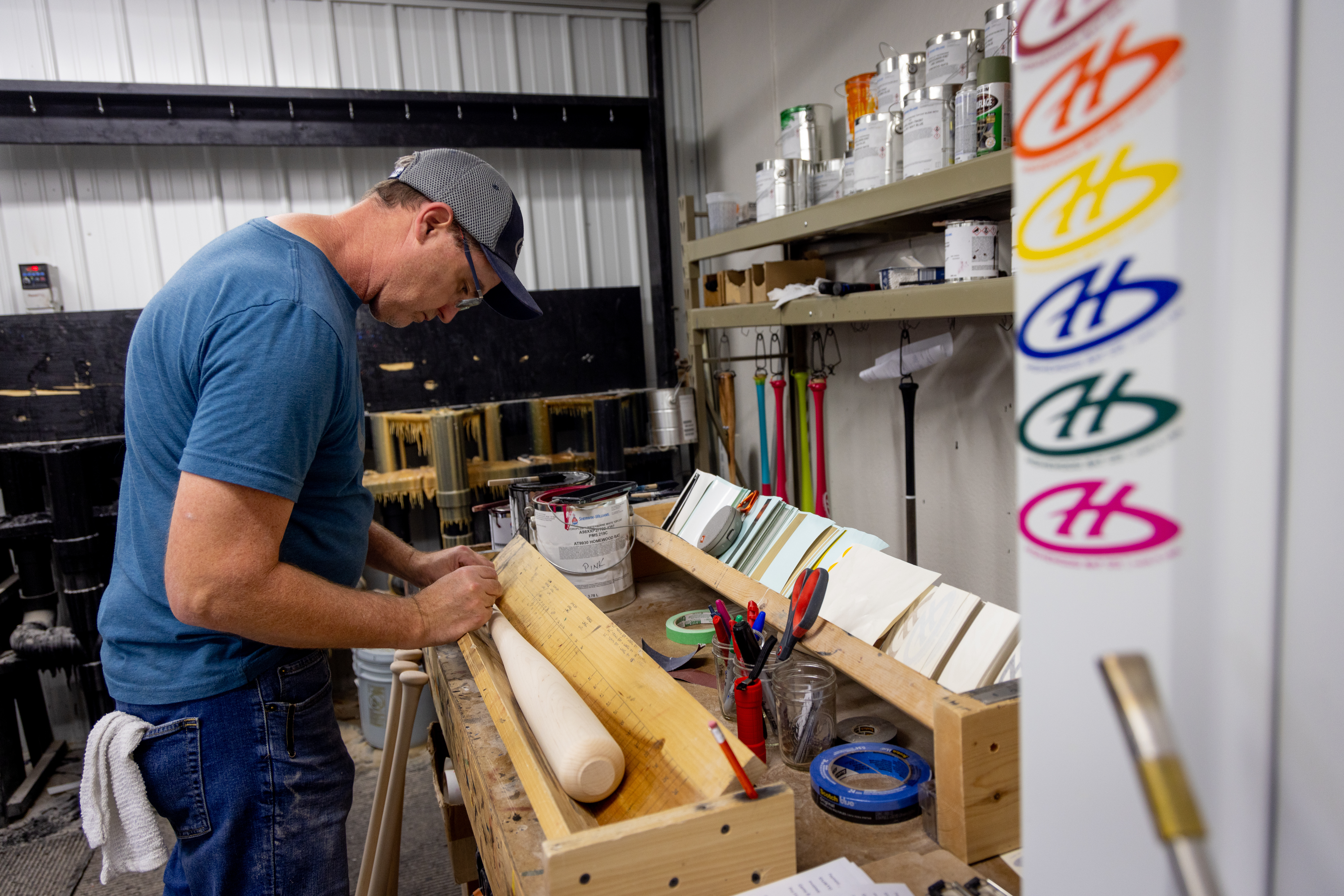 a bat maker painting an h with a circle around it on a bat