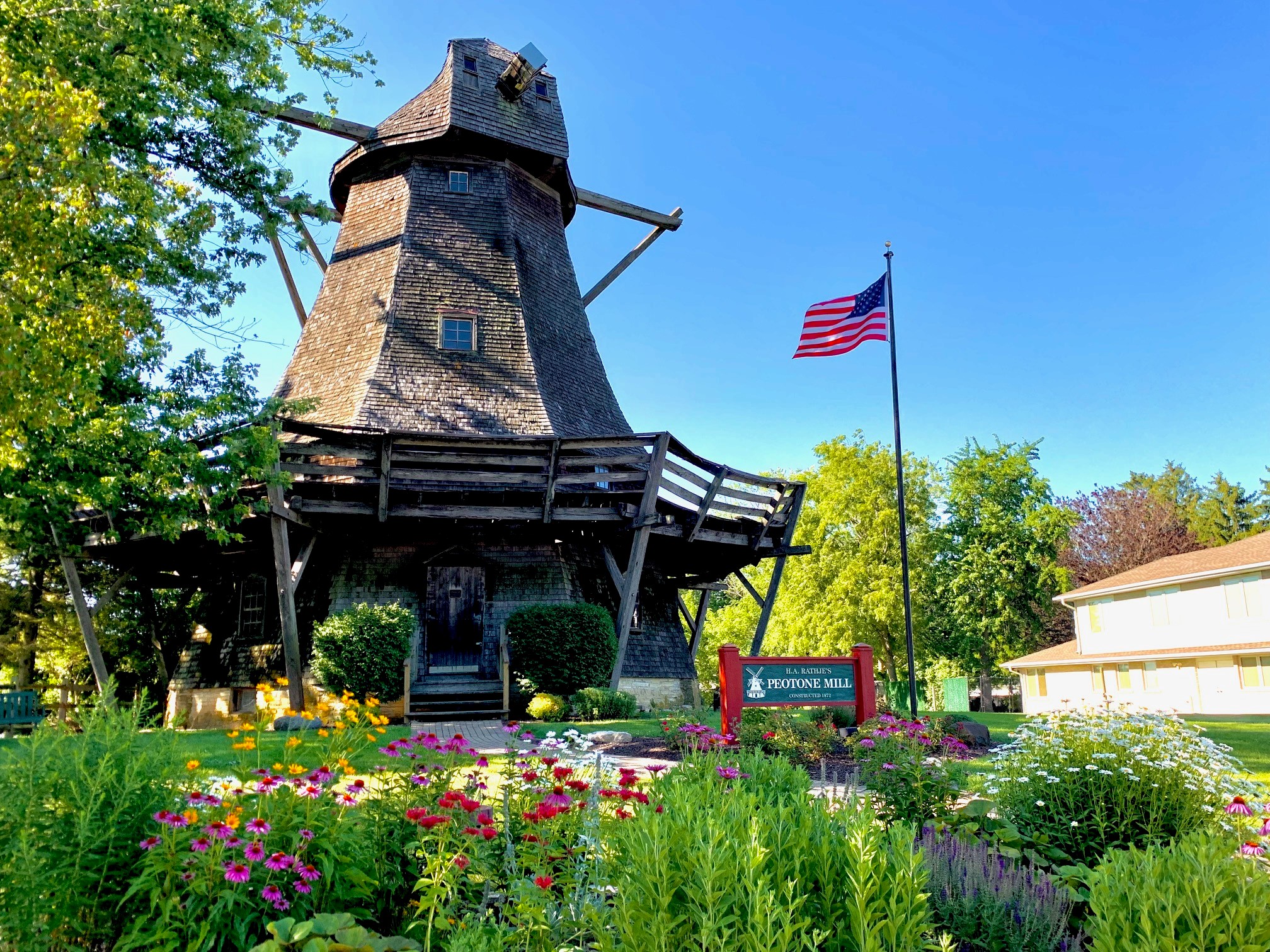 an old windmill iwth an american flag and tulips around it
