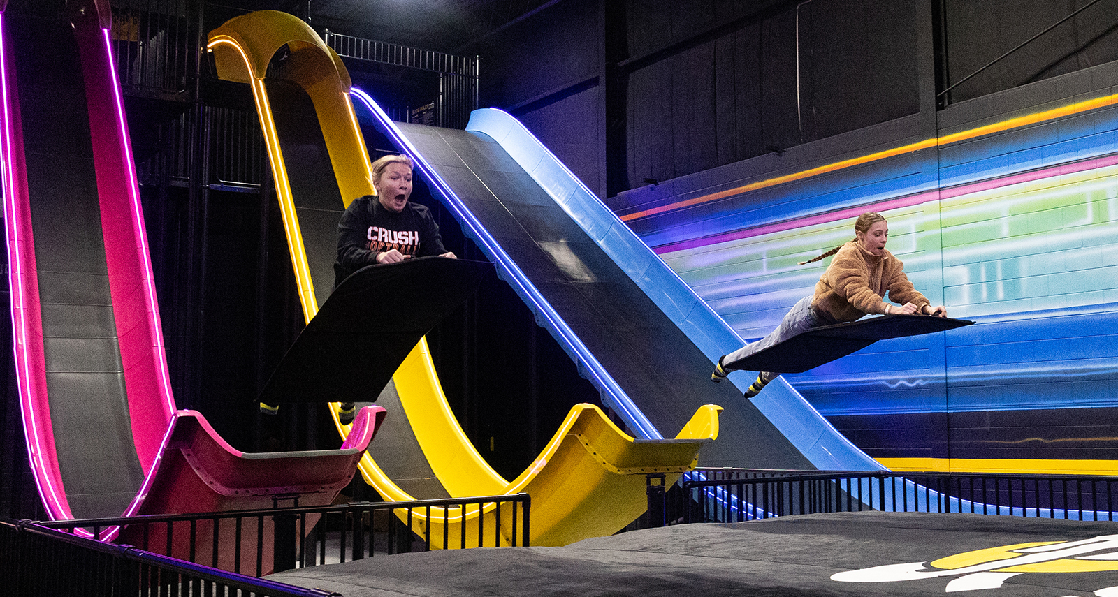 two girls sliding down an indoor slide park